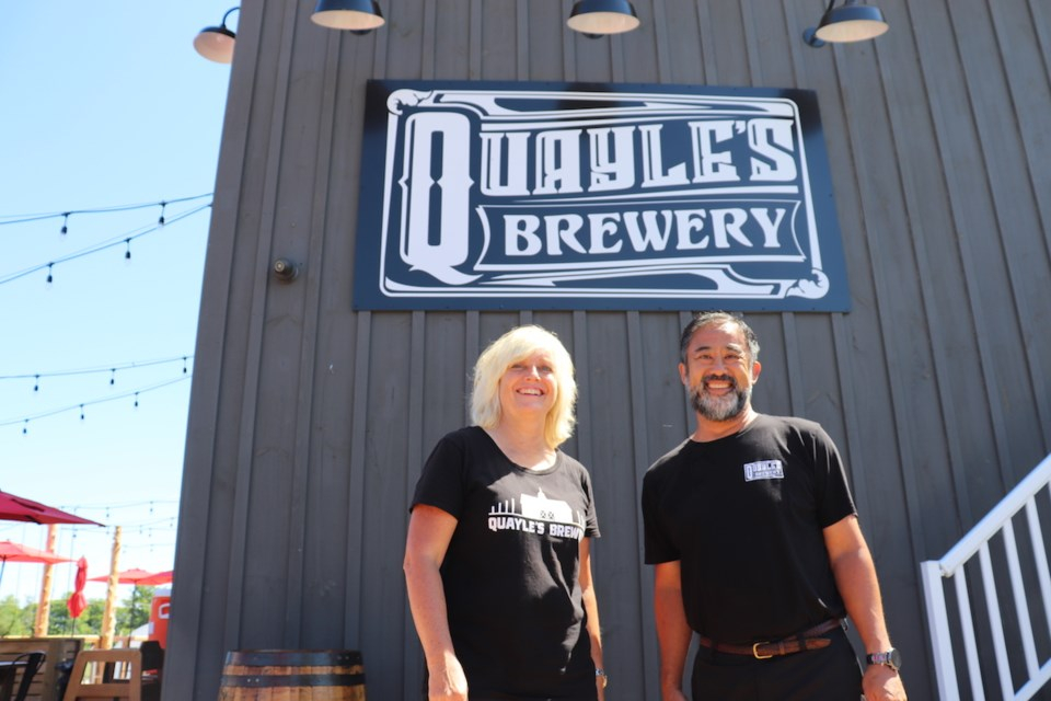 Owners of brewery standing in front of barn